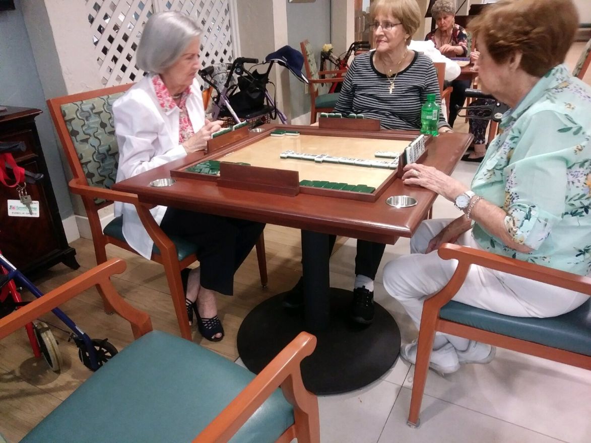 Residents enjoying a wheelchair-accessible pedestal domino table